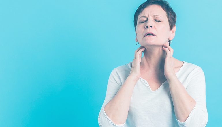 mujer tocandose el cuello con cara de dolor por cervicalgia postraumática
